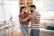 © Migma_Agency - Happy couple dancing together in living room at home