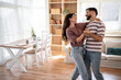 © Migma_Agency - Happy couple dancing together in their modern living room