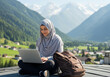 © Dezayn - Woman in Hijab Working Remotely on Laptop with Mountain View