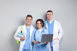 © New Africa - Group of medical students with laptop and books on light grey background