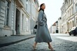 © SnapPik - woman strolling in retro coat on cobblestone street