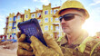 © Tahsin - Construction worker using tablet at construction site with building view