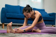 © PaeGAG - Asian woman doing stretching exercise on yoga mat at home in living room
