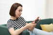 © New Africa - Woman using modern smartphone on sofa at home. Space for text