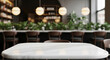 © PhotoArtHub - White marble table top, blurred cafe background with chairs and plants, showcasing free space for product display or advertisement