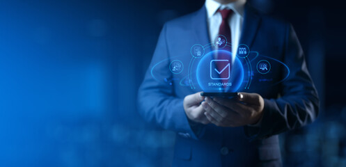 Wall Mural - businessman holding smartphone with standards icons on screen. quality management concept