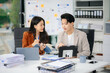 © laddawan - ￼￼Two young Asian professionals engaged in teamwork and business discussions in modern office