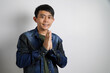 © yashis007 - Smiling young Asian man gesturing traditional greeting isolated over gray background