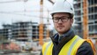 © Daiki - A young European male worker poses confidently at a construction site. Dressed in a safety vest and helmet, he embodies professionalism in modern building projects.