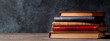 © Daniel - horizontal image of a top view of a stack of books Dark background with copy space for text. World Book Day concept. For banner, design, cover, thumbnail, social media, business, linkedin, presentat