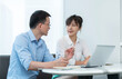 © xy - Two asian businesspeople working together in the office while using laptop