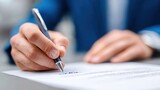 A person in a blue suit signs a document with a pen, focusing on the act of writing a signature on official paperwork