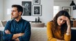 © Николай Срибяник - Upset couple sitting apart on sofa after argument, woman holding head in hands while man looks away with crossed arms in modern living room
