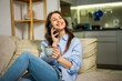 © Mediteraneo - Young Woman Talking on the Phone While Drinking Coffee at Home