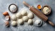 © Chingiz - Top-down view of raw dough balls, ingredients, and rolling pin on gray surface, space for text