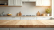 © Viktor - Empty wood table top in modern kitchen interior. Ready for product montage food presentation. Blurred clean bright background with white cabinets, decor, utensils, green plant in daylight. Wooden