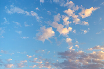 blue sky with scattered cumulus clouds illuminated by soft sunlight
