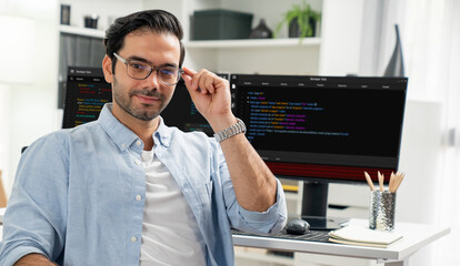Profile's smart IT developer looking camera to pose wearing glasses against on software development coding on two pc screen, presenting program update online website data at modern office. Surmise.