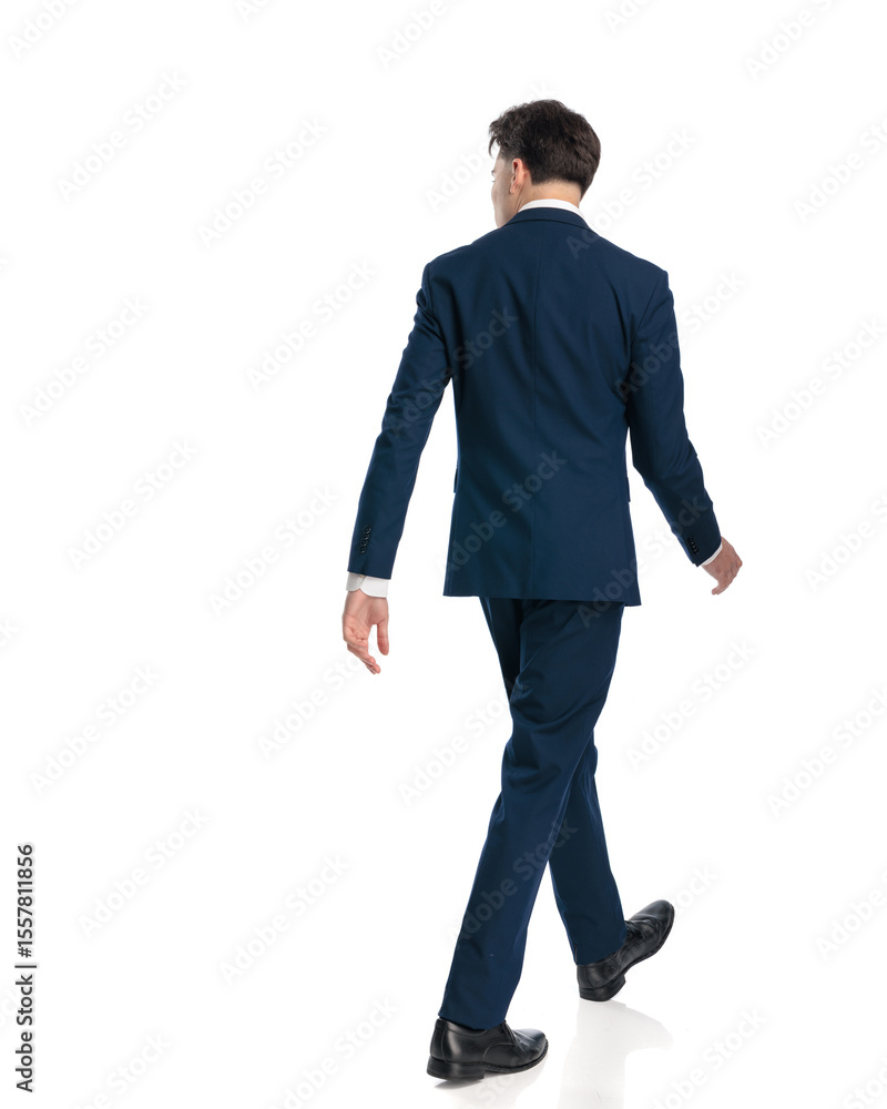 back view of elegant young businessman looking to side and walking ...