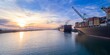 © Zenstratus - Cargo ships docked at the Port of Oakland, California, USA, are being loaded with shipping containers for global distribution at sunrise.