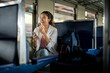 © bongkarn - Pretty asian woman holding phone looking away laughing as sitting on carriage bench at train station