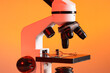 © Pixel-Shot - Modern microscope on orange background, closeup