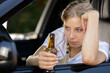 © auremar - drunk woman driving and holding beer bottle inside a car