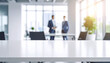 © Hyejin Kang - Close-up of a wide conference desk against a blurry modern bright office with worker background.