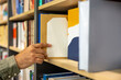 © zinkevych - Close up of a male hand touching a book on the shelf