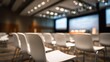 © hai - Modern white chairs arranged in rows in a dimly lit conference room with soft ceiling lights, large presentation screens, and a professional, quiet atmosphere.