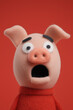 © Niaz - Surprised pink pig puppet character made of felt with wide open mouth and big eyes on red background for comic children animation illustration