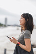 © Jirawatfoto - Happy young southeast asian woman, teenager blogger searching map smartphone, tourism guide. World travel explorer local cultural experience concept Chao Phraya river, Bangkok, Thailand, Asia