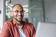 © Liubomir - A happy, smiling man with glasses looking to the side, wearing a red shirt, with soft lighting.