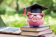 © Ram - Piggy bank with graduation cap and glasses on stack of books, student loan savings education budget, academic financial literacy, scholarship tuition planning, money saving for college funds
