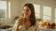 © Syuhuud - Young Woman Smiling with Smoothie in Bright Sunlit Kitchen, Surrounded by Fresh Fruits