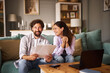 © Stockphotodirectors - A man and woman are engaged in a discussion about life insurance, reviewing documents, and enjoying each other's company in a warm and inviting living room.