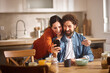 © Stockphotodirectors - A couple spends joyful moments in their home office, sharing smiles and laughter as they look at a smartphone. Natural light fills the room, enhancing the warm atmosphere.
