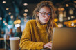 © mattegg - Young woman reading online blog on laptop in coffee shop