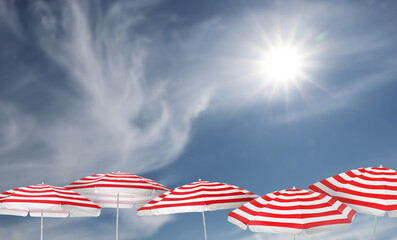 Wall Mural - red striped beach umbrellas against blue sky on sunny day