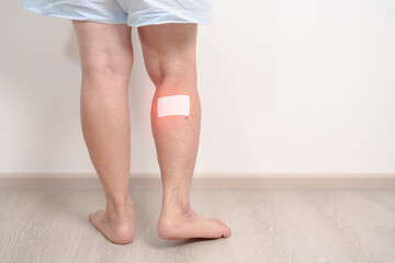 Elderly woman having Calf pain with Medicated pain relief patch plaster for concepts of Calf Muscle Strain, muscle pull, Leg Cramp, Sprain, aches, Varicose Veins, Deep Vein and world Thrombosis day