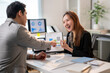 © Apichat - A man and a woman are sitting at a desk with a presentation in front of them