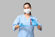 © Pixel-Shot - Portrait of female doctor in mask showing test tube with blood sample on grey background