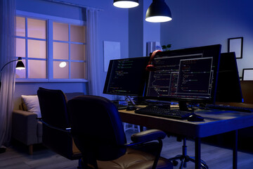 Wall Mural - programmer's desk with computer monitors and glowing lamps in dark office at night