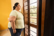 © GAJENDRRA BHATI  - Obese indian woman feels lonely at home. Plus size lady standing alone near window . Stress and Mental health problem due to obesity.