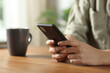 © PheelingsMedia - Woman hands texting on mobile phone on wooden table
