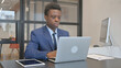 © stockbakers - Young African Businessman Typing on Laptop at Workplace