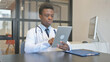 © stockbakers - African Male Doctor Using Digital Tablet