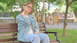 © stockbakers - Young Woman Massaging Her Neck on a Park Bench