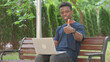 © stockbakers - Casual African Man Giving Thumbs Up with Laptop Outdoors