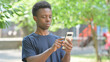 © stockbakers - Casual African Man Using Smartphone Internet Outdoors